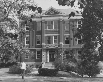 An unidentified man is walking by Frazee Hall. Frazee Hall was built in 1907 and named after David Frances Frazee on June 3, 1931. On January 24, 1956, the building was partially destroyed by a fire. Received August 17, 1957 from Public Relations