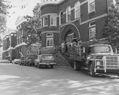 Four unidentified men are moving a desk into the Gillis Building (then called the Administration Annex). The Gillis Building was built in 1892 and on April 4, 1978, it was named after Ezra Gillis