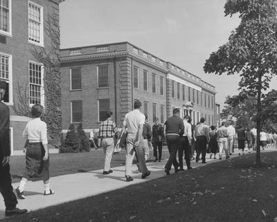 Unidentified students are walking past the Journalism Building in the 1957 
