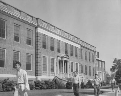 Six unidentified men are walking past the Journalism Building in the 1957 