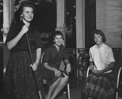 At the Hamilton House--sweeping the porch is Gayle Shoemaker, behind her are: Betty Reid (left), Elanor Burkhard. The house is for Home Economic use. Received September 25, 1958