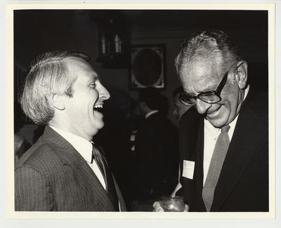 President Singletary (standing, right) is laughing with Lt. Governor Steve Beshear (standing, left).  Beshear is a University of Kentucky Alumnus and they are at a honorary reunion
