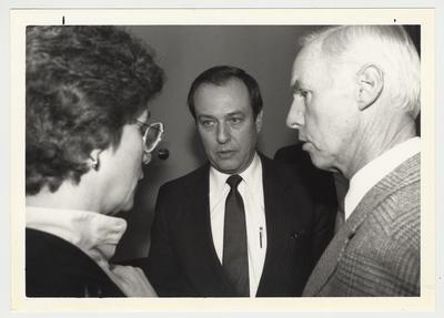 President Charles Wethington (standing, center) is conversing with Carolyn Brott (left) and Mr. Leigh (right) during a UK vs Florida game