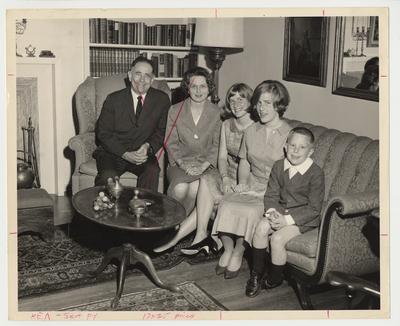 The Oswald Family are seated together in a living room.  From the left:  President Oswald, his wife Rosanel, Elizabeth, Nancy, and Johnny
