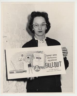 Betty Dickey is holding a Civil Defense sign for fallout shelters
