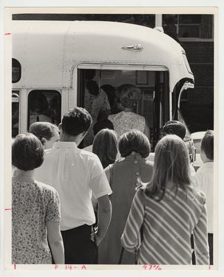 Unidentified students are boarding a bus.  This bus was part of the new campus bus service, which began in 1969