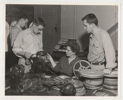 Four people are working with film for the University Extension program at the University of Kentucky.  University Extension was the forerunner to distance learning.  From the left:  Sam Gilkey Jr., Paducah, KY;  Derald Hunt, Cheyenne, OK;  Mrs. Ann Flewelling, and Norman Schott, Louisville, KY