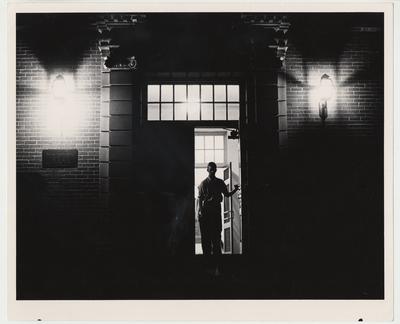 An unidentified man is walking out of the Margaret I. King Library at night