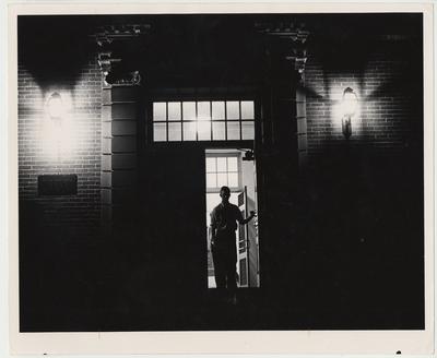 An unidentified man is walking out of the Margaret I. King Library at night