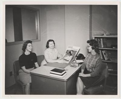 Jennifer Jones and two unidentified women are looking at a poster that says 