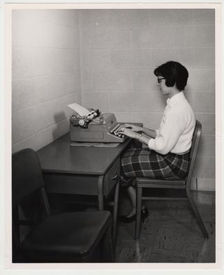 An unidentified woman typing on a type writer