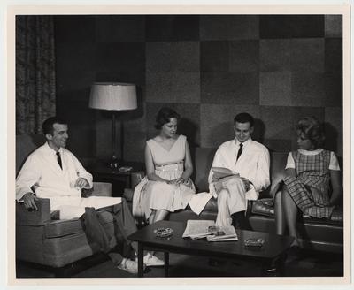Two unidentified men and two unidentified women are conversing in a sitting room
