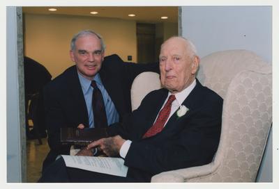 Provost Michael Nietzel (left) is handing Thomas Clark (right) a book at Dr. Thomas D. Clark's 100th birthday celebration at Young Library