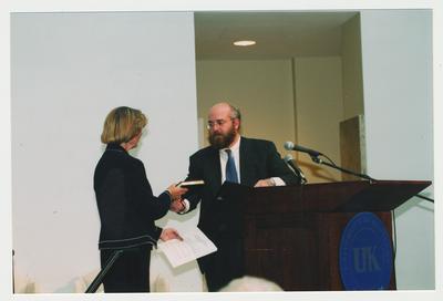 Stephen Wrinn (right), Director of the University Press of Kentucky, is presenting the three millionth book to Carol Diedrichs (left), Dean of Libraries, at Dr. Thomas D. Clark's 100th birthday celebration at Young Library