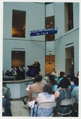 Stephen Wrinn (seated, left), Director of the University Press of Kentucky, and unidentified people are listening to Thomas Clark  speak at Dr. Thomas D. Clark's 100th birthday celebration at Young Library