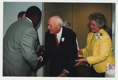 Patricia Todd (right) is watching Thomas Clark (center) shake hands with Everett McCorvey (left), who sang Happy Birthday to Thomas Clark at Dr. Thomas D. Clark's 100th birthday celebration at Young Library