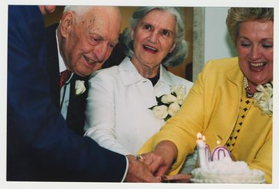 Patricia Todd (right) and Loretta Brock (second from right) are helping Thomas Clark (second from left) cut his birthday cake at Dr. Thomas D. Clark's 100th birthday celebration at Young Library