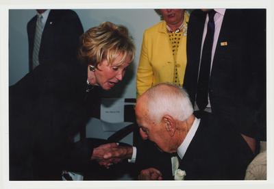 Sue Wylie (left), radio personality, is talking to and shaking hands with Thomas Clark (right) at Dr. Thomas D. Clark's 100th birthday celebration at Young Library
