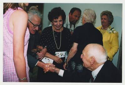 David Zageer (center, shaking hands) and Mrs. Zageer are talking with Thomas Clark at Dr. Thomas D. Clark's 100th birthday celebration at Young Library