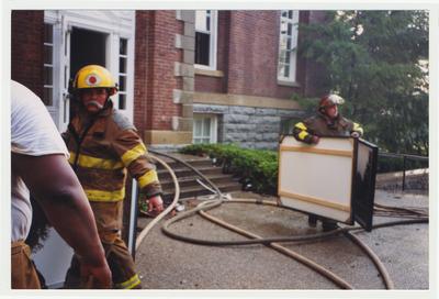 Unidentified fire fighters are bringing large photos out of the Administration Building after the fire was extinguished