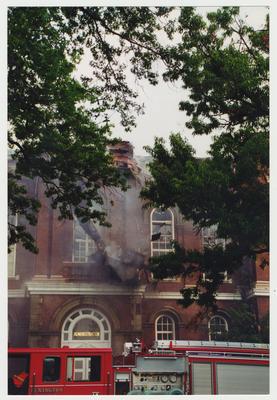 An exterior view of the Administration / Main Building during the fire.  A fire truck is in front and there is quite a bit of smoke