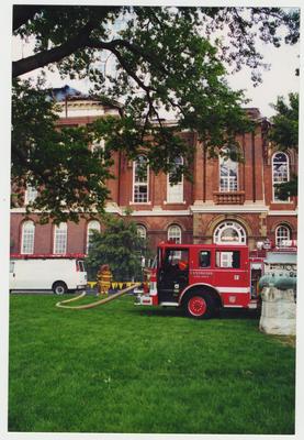 A fire truck  and unidentified fire fighters are outside of the Administration / Main Building during the fire