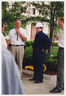 President Wethington (center, blue coveralls and a white hat), Harold Tree Sandford (far right) and two unidentified men are standing outside of the Administration / Main Building during the fire