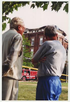 Two unidentified men are standing outside of the Administration / Main Building during the fire