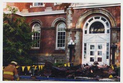 An unidentified fire fighter is accessing the damage that the fire did to the Administration / Main Building.  There is a pile of debris in front of the door to the building