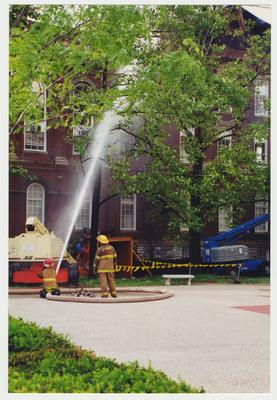 Two unidentified fire fighters are spraying water on the Administration / Main Building to extinguish the fire