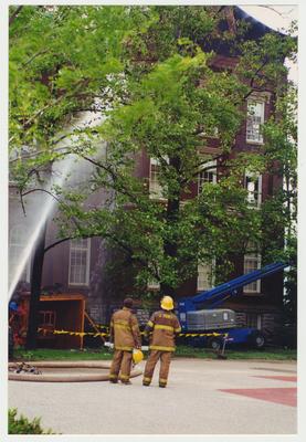 Two unidentified fire fighters are watching water being sprayed on the Administration / Main Building to extinguish the fire