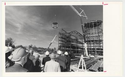 Unidentified people are watching as the six ton cupola of William T. Young Library being raised onto the building during construction
