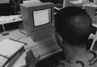 An unidentified man is working on a computer in the computer lab