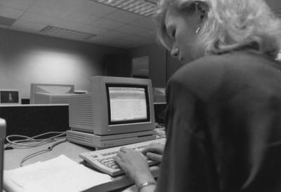 An unidentified woman is typing a paper in the computer lab