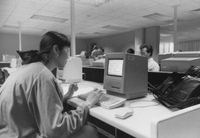 An unidentified woman is looking at a computer in the computer lab