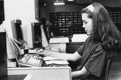 An unidentified woman is working on a computer in the reference room