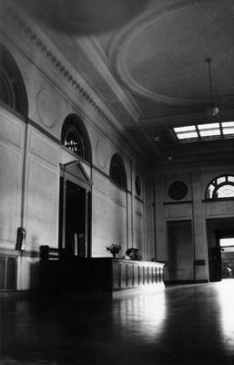 An unidentified woman is seated at the circulation desk in the Great Hall in King Library