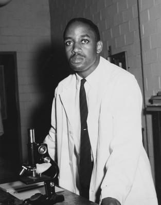 Carl Weber Watson, class of 1960, stands before a microscope