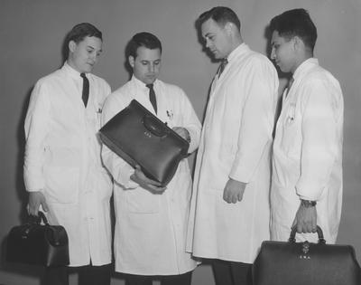 Members of UK College of Medicine's Class of 1964 (first class accepted by the college) examine a black leather medicine kit. From left to right: Richard E. Geist, Martin Gebrow, Thomas W. Hagan, and Manuchehr Alavi. Received February 21, 1962 from Public Relations