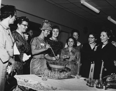 An unidentified woman is pouring punch in to cups and serving to women, at the dedication of the Medical Center