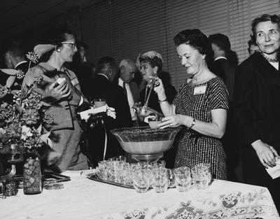 An unidentified woman is pouring punch in to cups and serving to women, at the dedication of the Medical Center