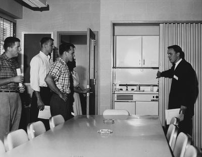 Four men and a woman are looking at a cabinet / sink combination at the dedication of the Medical Center