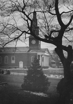 View of Memorial Hall through bare tree, with small amount of snow on the ground