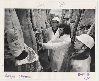 Unidentified men are looking at meat in the meat processing division