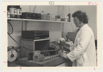 Technician, Charlie Potter, in a lab coat looking at laboratory equipment.  Soil testing laboratory procedure improved