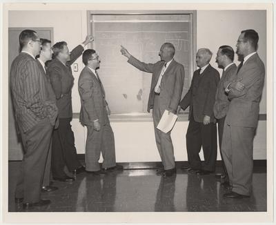 Members of the Committee on Educational Policy and Curriculum discuss the number of hours to be devoted to each area of study.  From the left:  Dr. Alan Ross, Dr. Robert E. McCafferty, Dr. William Knisely, Dr. Robert Straus, Dean William R. Willard, Dr. Joseph Parker, Dr. Edmund Pellegrino, and Dr. George Schwert