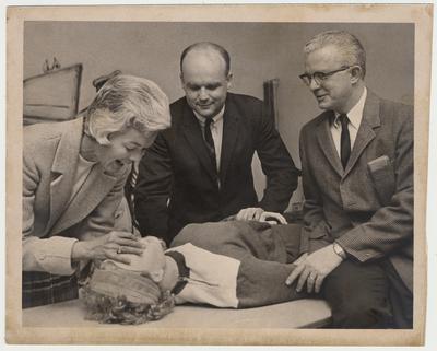 From the left:  Mrs. Betty Luisant, Dr. Peter Bosomworth, and Dr. Charles Mobler demonstrate a medical technique on a mannequin