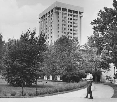 View of Patterson Office Tower from Southeast, with student reading as he walks