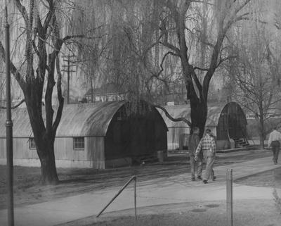 Three male students walking past Huts used by the Music Department. Photographer: W. E. Sutherland. Received April 20, 1967 from Public Relations