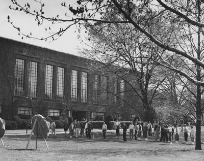 Students shooting arrows at target out front of Student Union before remodeling. Received April 15, 1957 from Public Relations